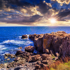 sea ​​wave breaks about boulders at sunset