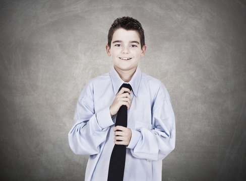Young boy with blue shirt adjusting his tie
