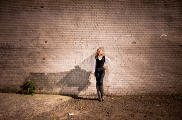 Beautiful blonde woman leaning against long tiled wall on street