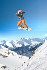 Naklejka na ściany i meble Extreme snowboarding man jumping high in the air