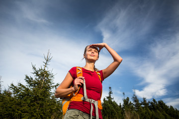 Obraz premium Pretty, female hiker going downhill in warm evening light