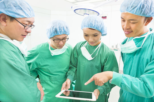 surgeons discussing with tablet in operating theater
