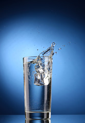 fresh water in glass with ice cubes on blue background