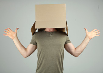 Man with cardboard box on his head on grey background