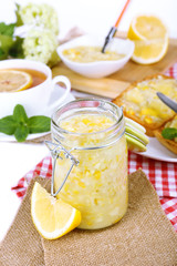 Tasty lemon jam with cup of tea on table close-up