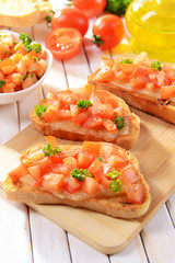 Delicious bruschetta with tomatoes on cutting board close-up