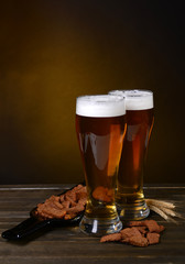 Glasses of beer with snack on table on dark background