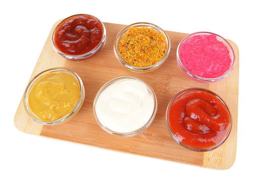 Various sauces on chopping board isolated on white