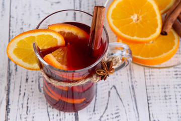 Mulled wine with oranges and spices on wooden background