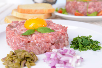 Delicious steak tartare with yolk on plate on table close-up
