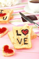 Delicious toast with jam and cup of tea on table close-up