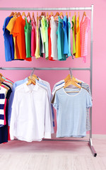 Different clothes on hangers, on pink background