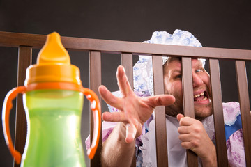 Man weared as baby trying to reach out the bottle