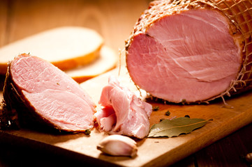 Whole ham with bread in the background, selective focus