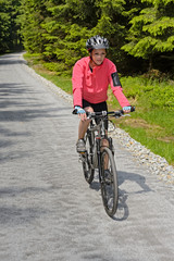 Fototapeta premium Woman riding bike on sunny cycling path