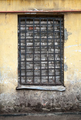 Old yellow building facade with locked window