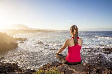 Fototapeta na wymiar young woman practicing yoga meditation on the beach at sunset