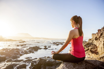 Fototapeta na wymiar young woman practicing yoga meditation on the beach at sunset