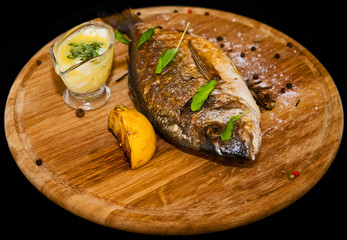 Grilled fish with lemon and spices on a wooden board