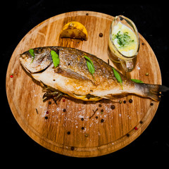 Grilled fish with lemon and spices on a wooden board