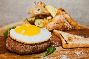 Scrambled eggs on meat with fried potatoes and toast