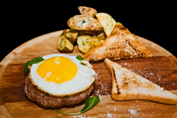 Scrambled eggs on meat with fried potatoes and toast