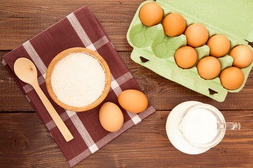 Eggs, milk and flour on a wooden table