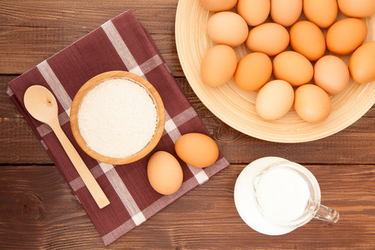 Eggs, milk and flour on a wooden table