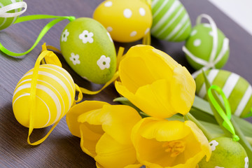 Farbenfrohe gelbe Tulpen mit grünen Blättern und Ostereiern zu