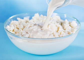 milk pouring into bowl with cottage cheese