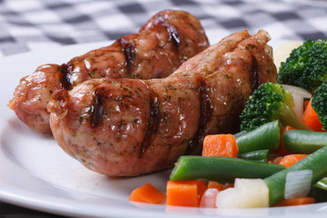 Hot sausages grilled with vegetables on a white plate