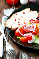 Set of oven baked pork in plate with salad on table