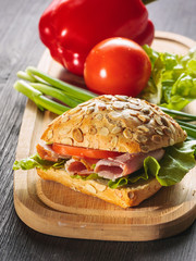 Fresh ham sandwich on wooden board - close up