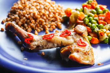 Oven baked rabbit legs with green peas and carrot