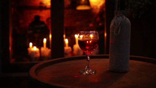 Wine bottle with glass on the wooden barrel cozy bar still life