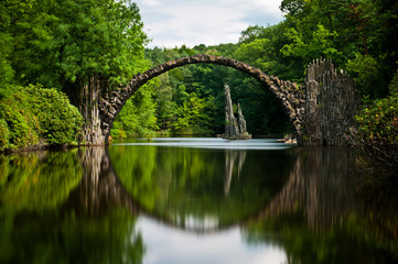Very old stone bridge over the quiet lake
