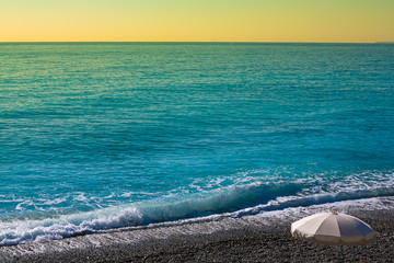 Fototapeta na wymiar Empty beach with sun umbrella, sea and waves