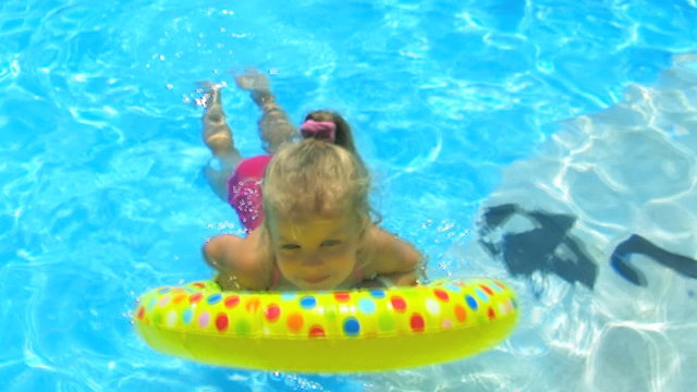 Children  on inflatable ring in swimming pool.