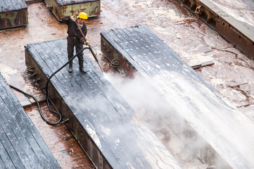 Worker cleaning dry dock in Gdansk shipyard