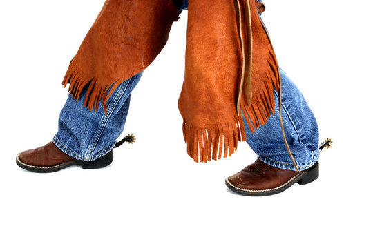 legs of a young cowboy wearing chaps spurs and boots
