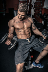 Fototapeta na wymiar Muscled guy lifting dumbbells