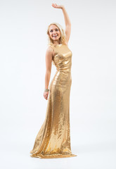 Beautiful female fashion model posing in gold dress