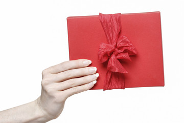 Hand holding red present box with big bow isolated on white back