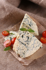 Tasty blue cheese with tomatoes and basil, on burlap background