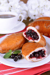 Fresh baked pasties with currant on plate on table close-up