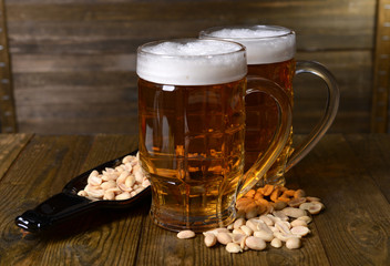 Glasses of beer with snack on table on wooden background