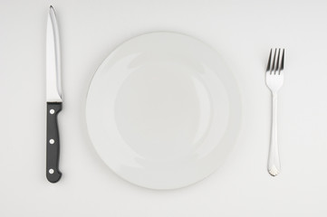 Knife,fork and plate on grey background