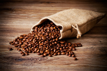 The sack of coffee beans on wooden background