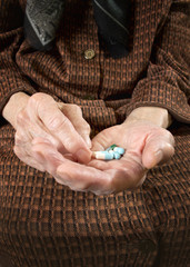 Senior woman holding assorted capsules in her hands.