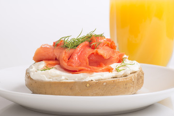 Freshly baked bagel with cream cheese, lox and orange juice